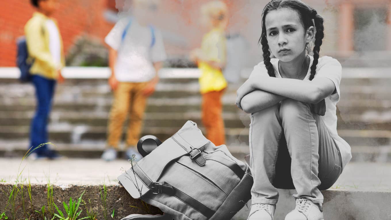 Little girl sitting on the steps of her school, with her backpack