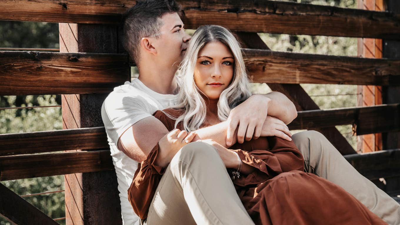 couple sitting in front of a fence