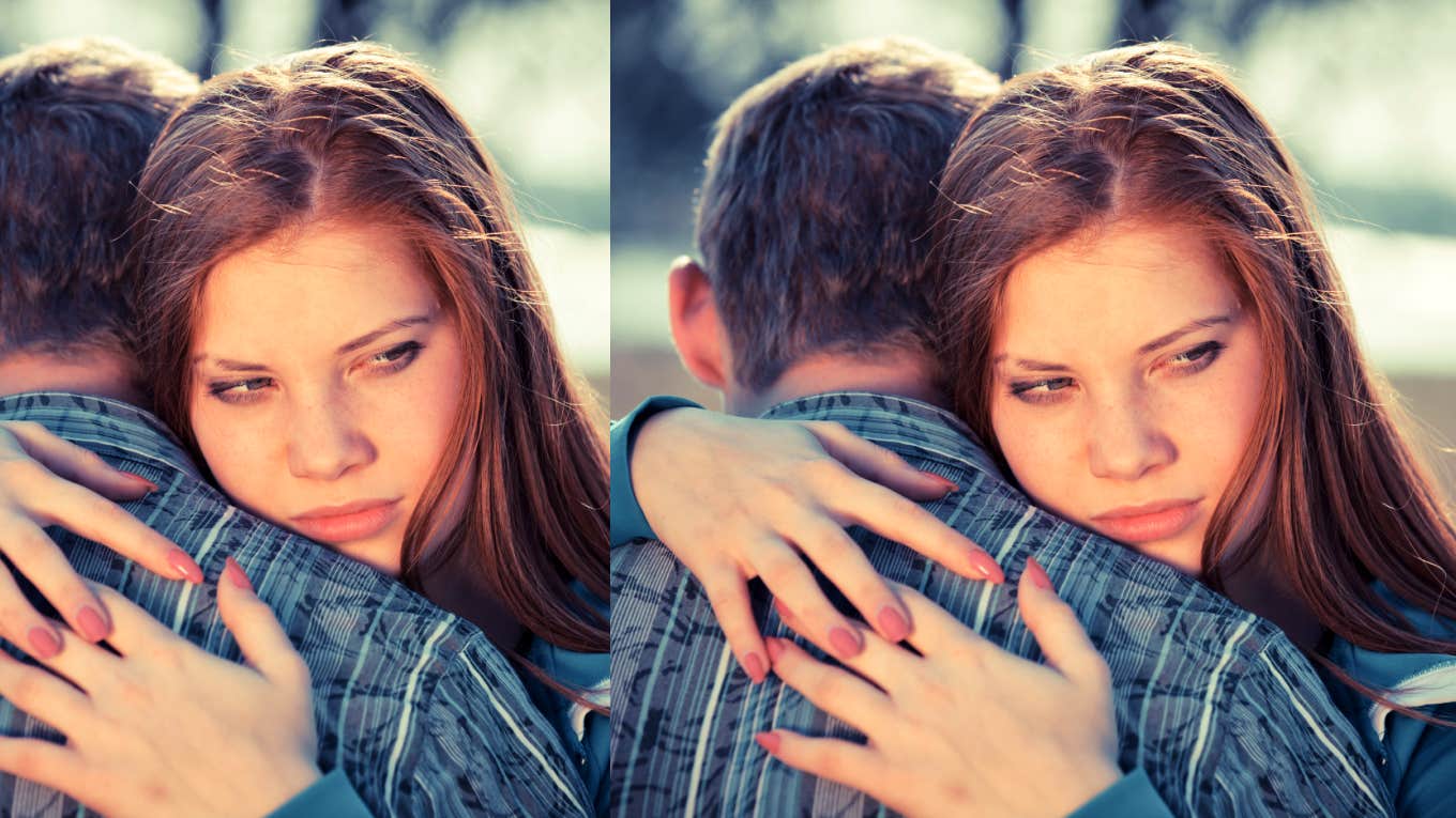 woman looking over man's shoulder as she hugs him