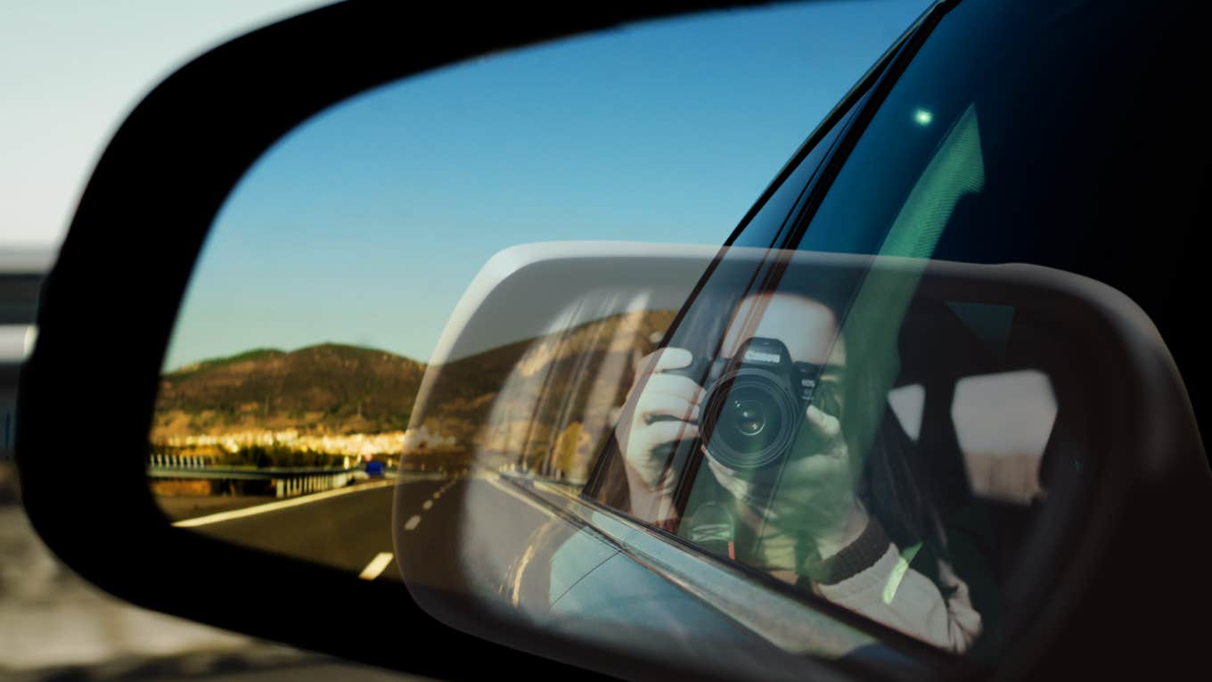 Woman taking photo of herself and the road behind her 