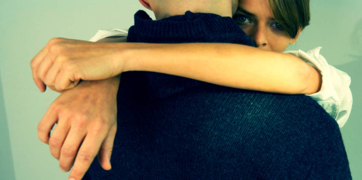 couple hugging with woman peeking over man's shoulder