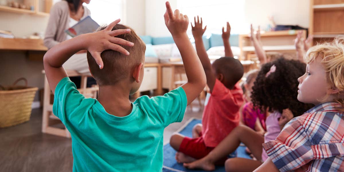 Children in a classroom holding up their hands