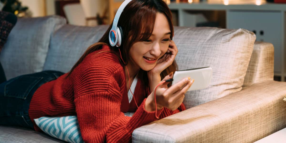 girl lying on couch watching video on phone