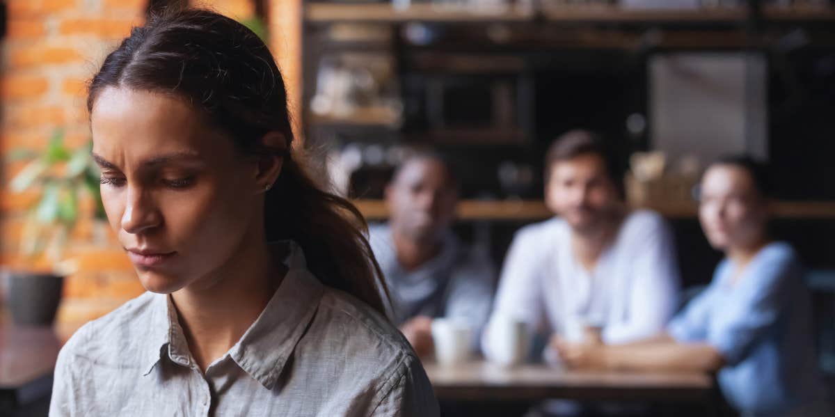 The Type Of Baggage You Shouldn't Have To Carry From Toxic Family Members, According To Experts upset woman with people looking on in the background