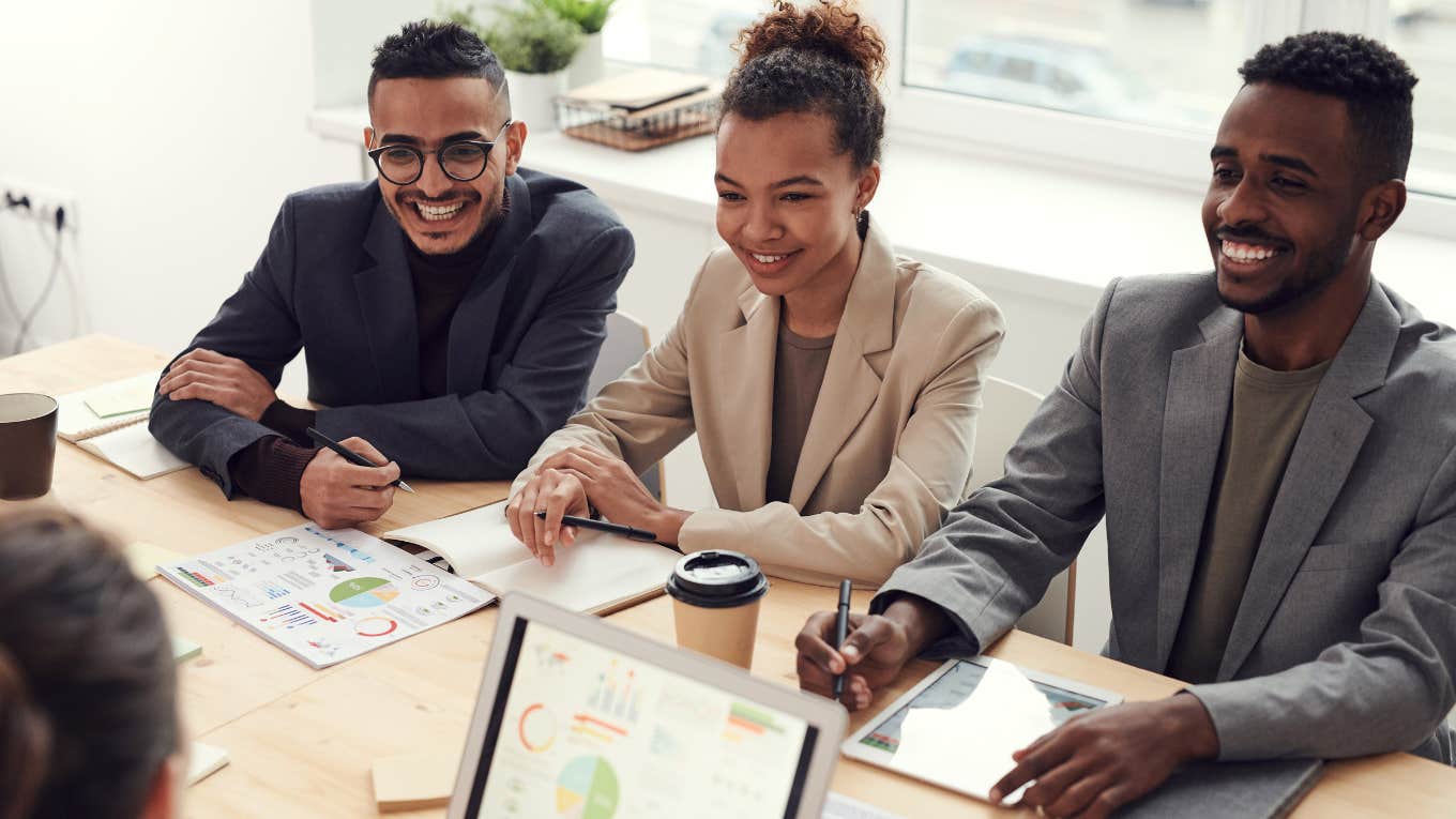 Photo of Three People Smiling While Having a Meeting