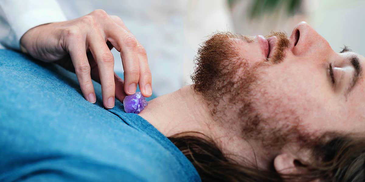 man holding a crystal to his throat