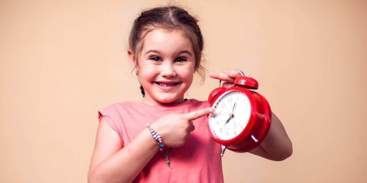 little girl pointing at a red clock