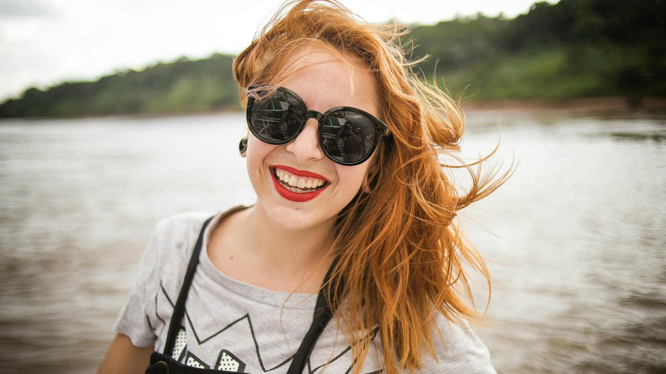 11 Tiny Tasks That Alleviate Loneliness happy woman smiling wearing sunglasses