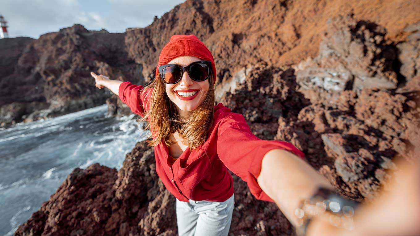 woman takes a selfie on a cliff near the ocean