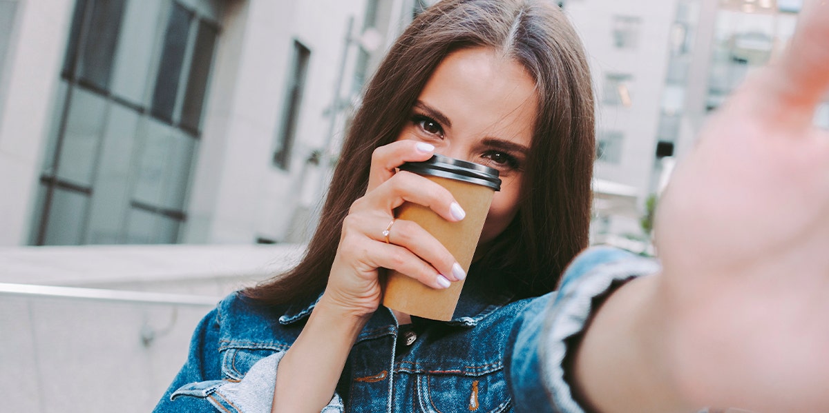 woman holding a cup of coffee hiding her face