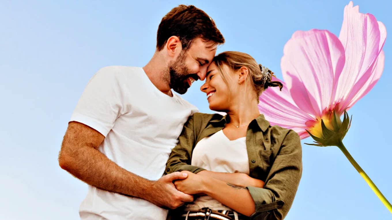 couple in front of a blue sky and big pink flower 