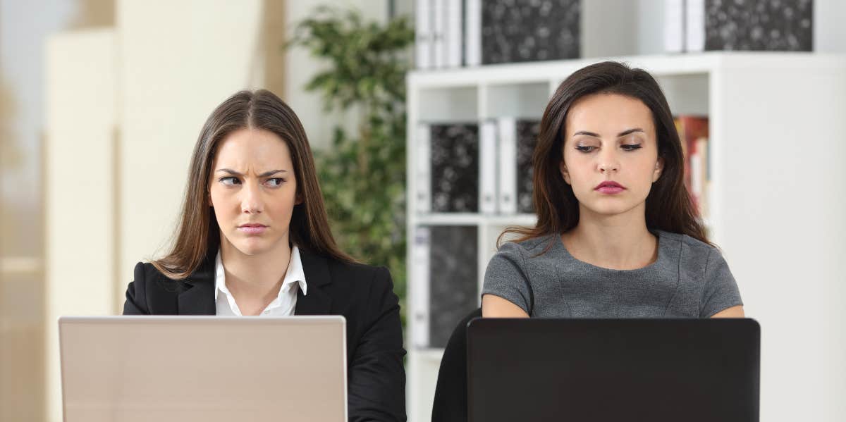How To Deal With A Coworker Who Is Out To Get You two women side-eyeing one another at work