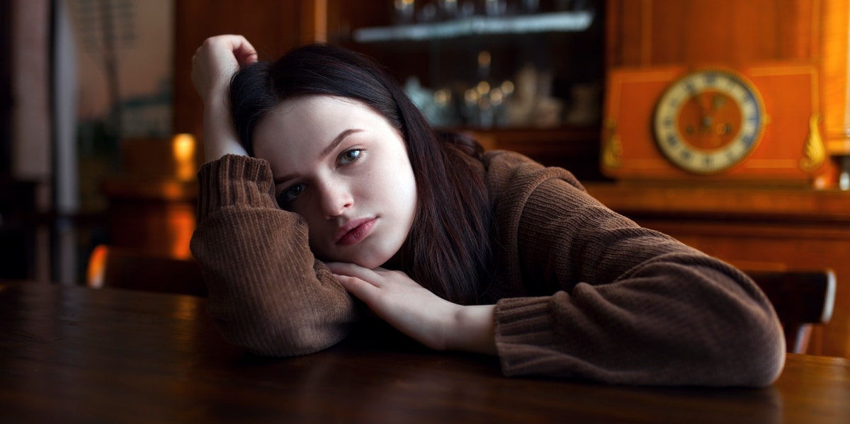 glum-looking woman with her head on the table