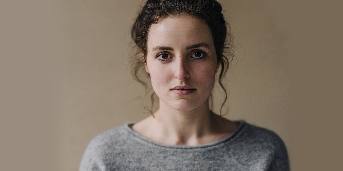 woman in dark hair ponytail looking straight at camera