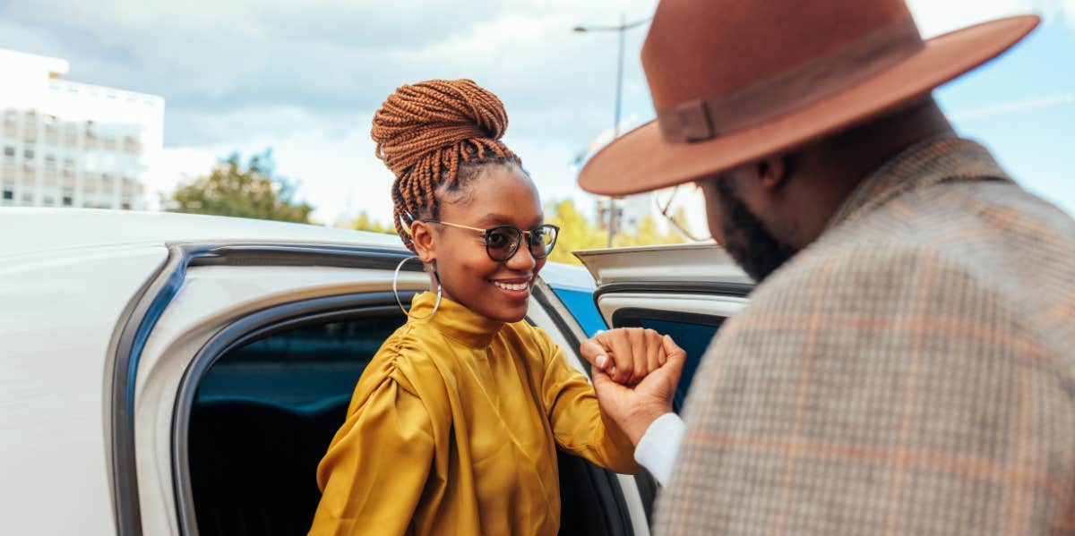 classy woman is helped out of the car by a man