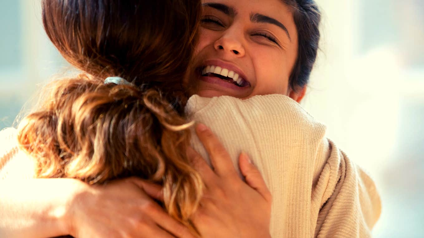 woman smiling while hugging her friend