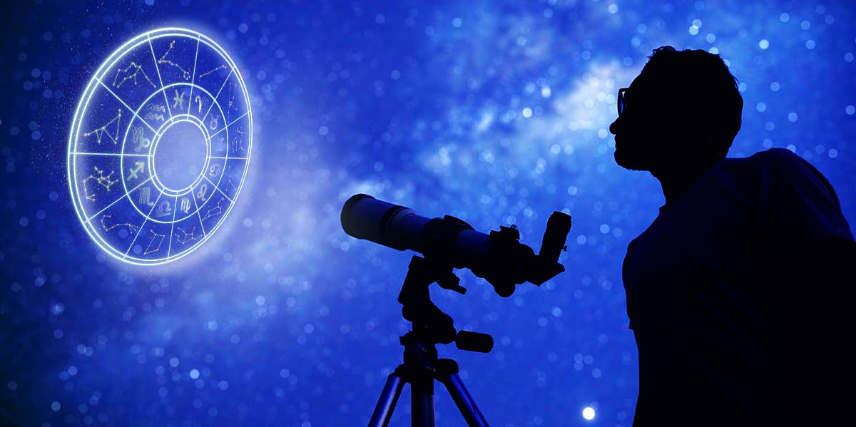 man looking through telescope at zodiac wheel
