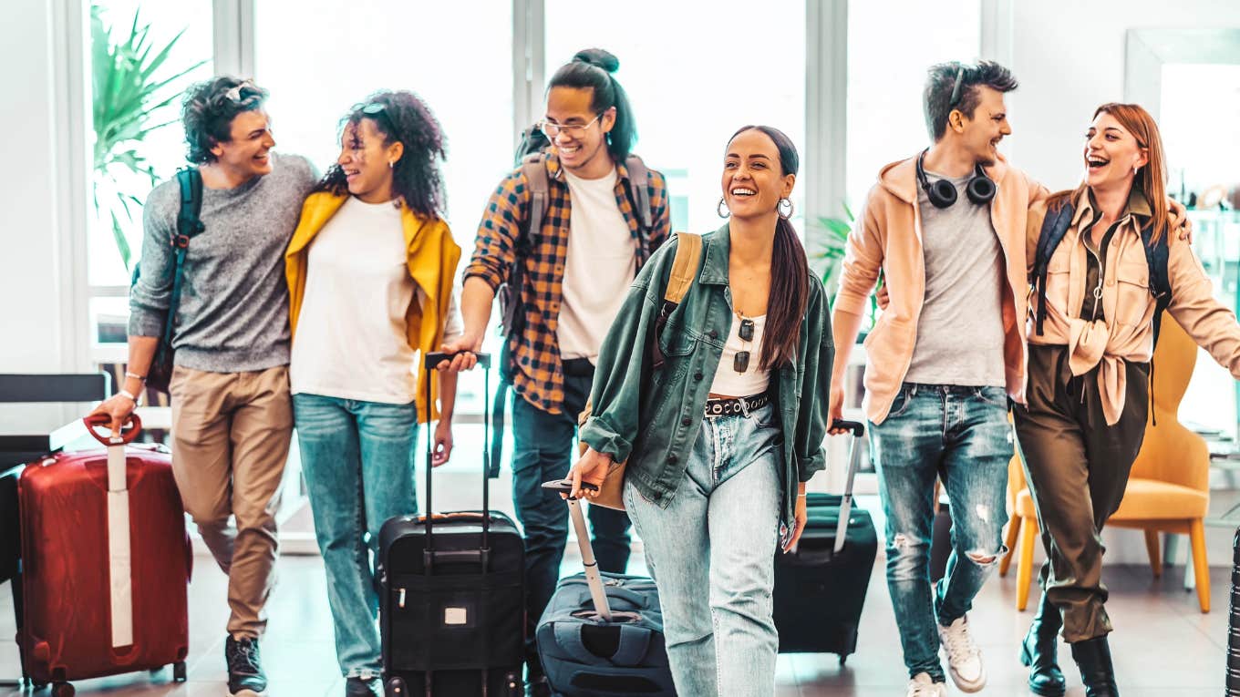 smiling friends arriving with suitcases for vacation