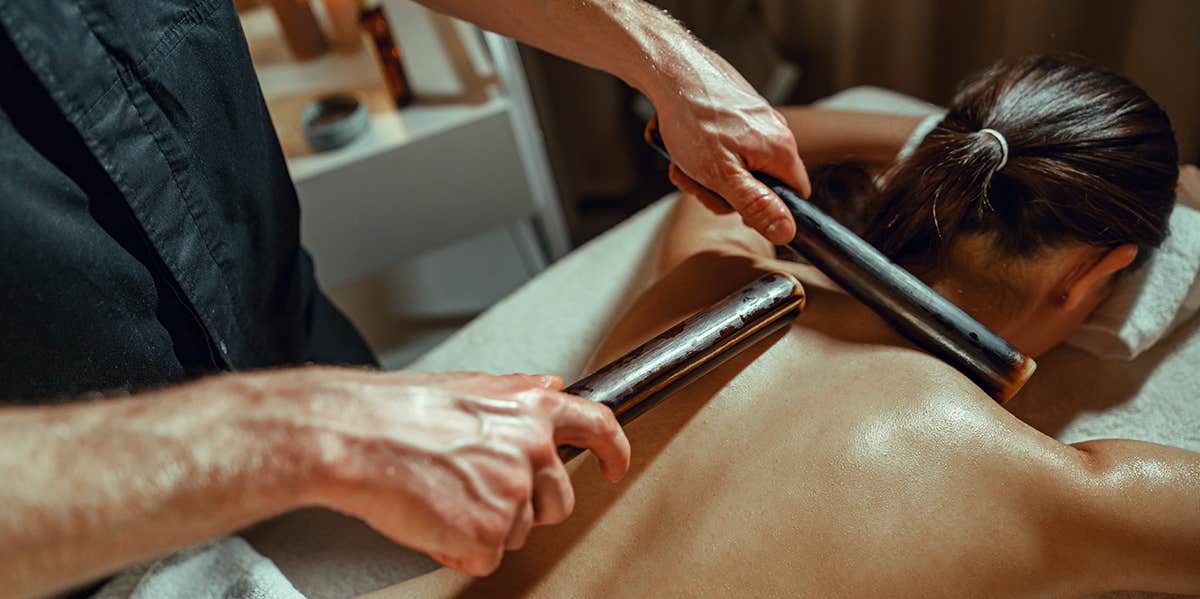 back massage on woman using bamboo canes