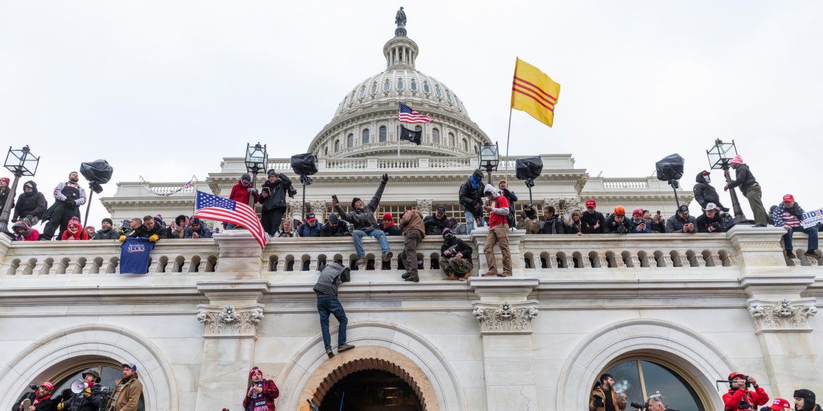 rioters climb the walls of the Capitol building on January 6, 2021