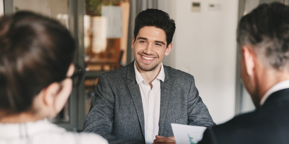  man smiling while sitting in front of people