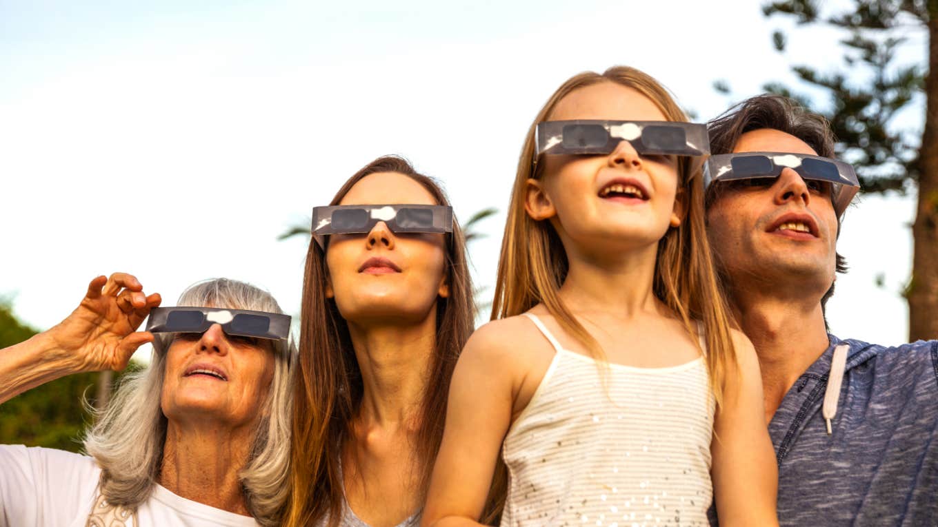 family wearing eclipse glasses witnessing a solar eclipse