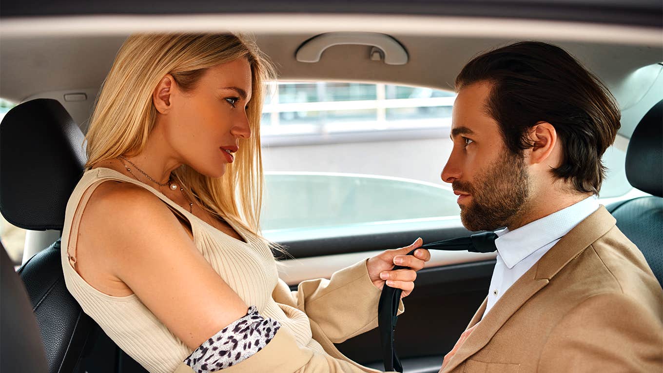 woman pulling mans tie in car