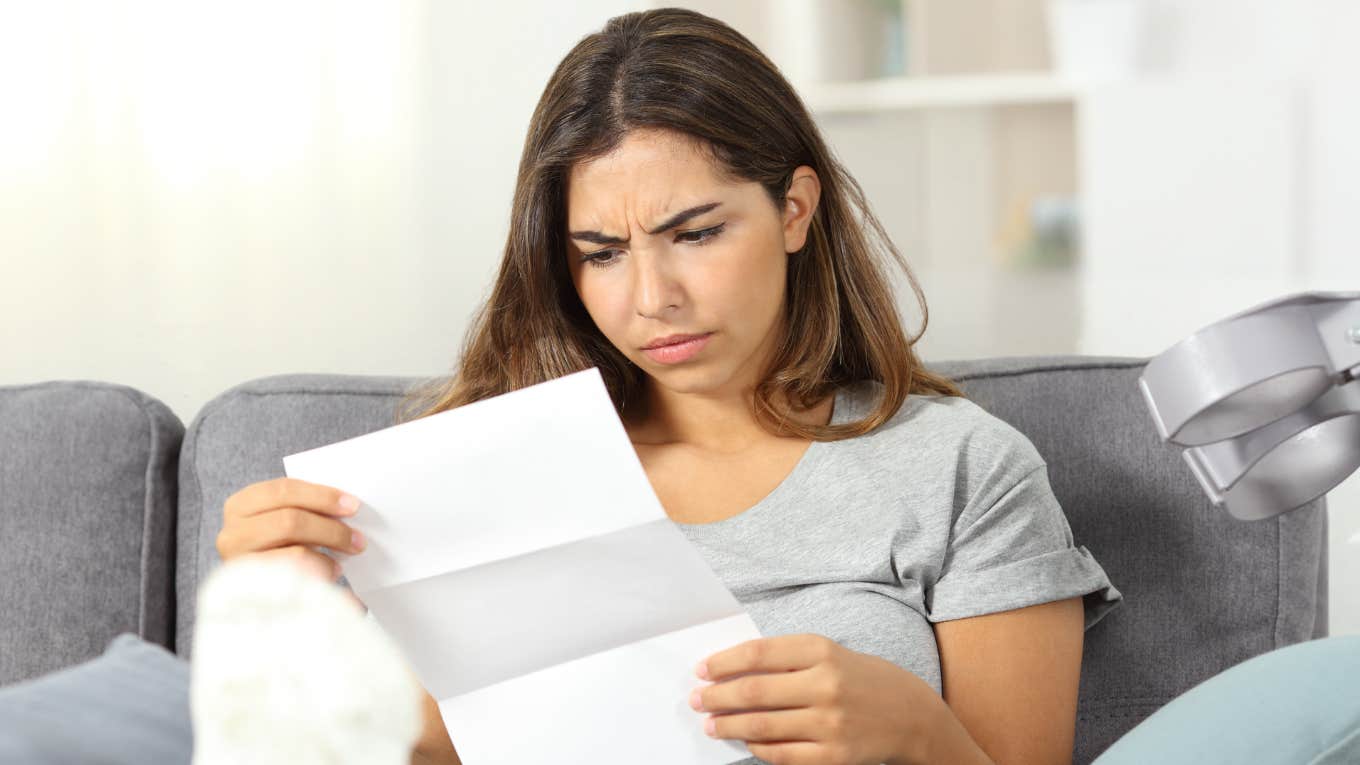 Woman reading a love letter on a couch. 