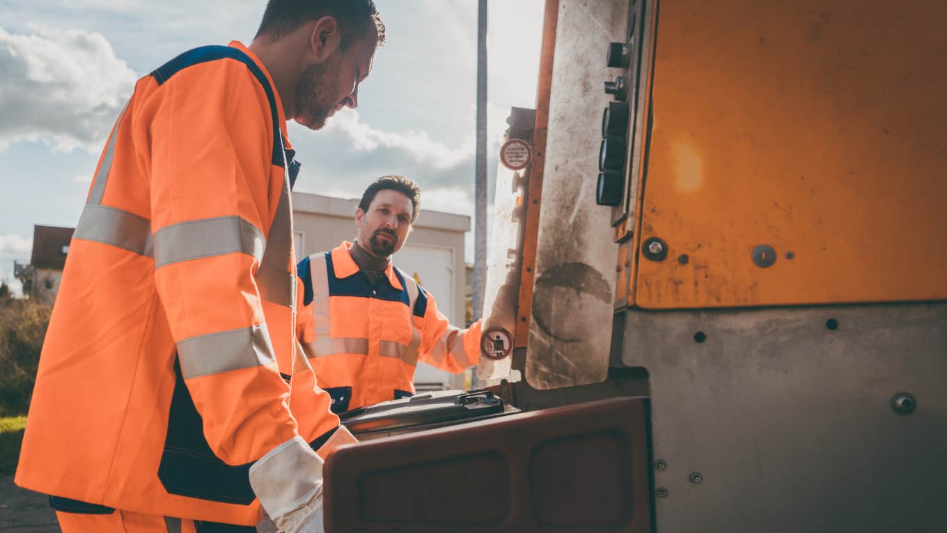 Garbage removal men working for a public utility emptying trash container