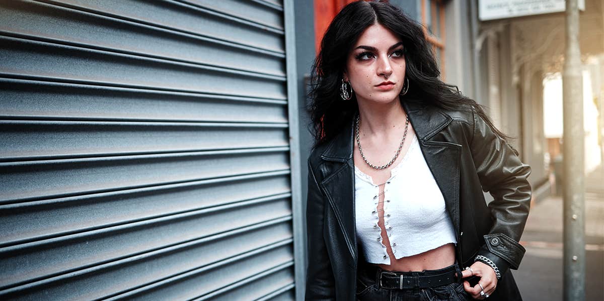 confident woman posing outside by wall