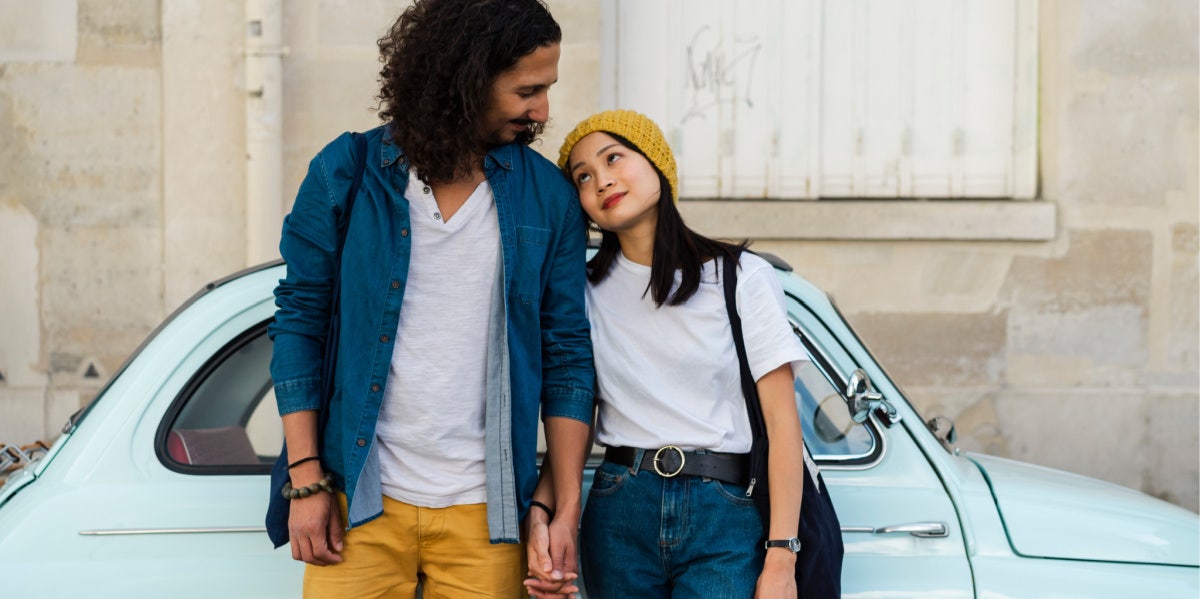 couple holding hands in front of a car