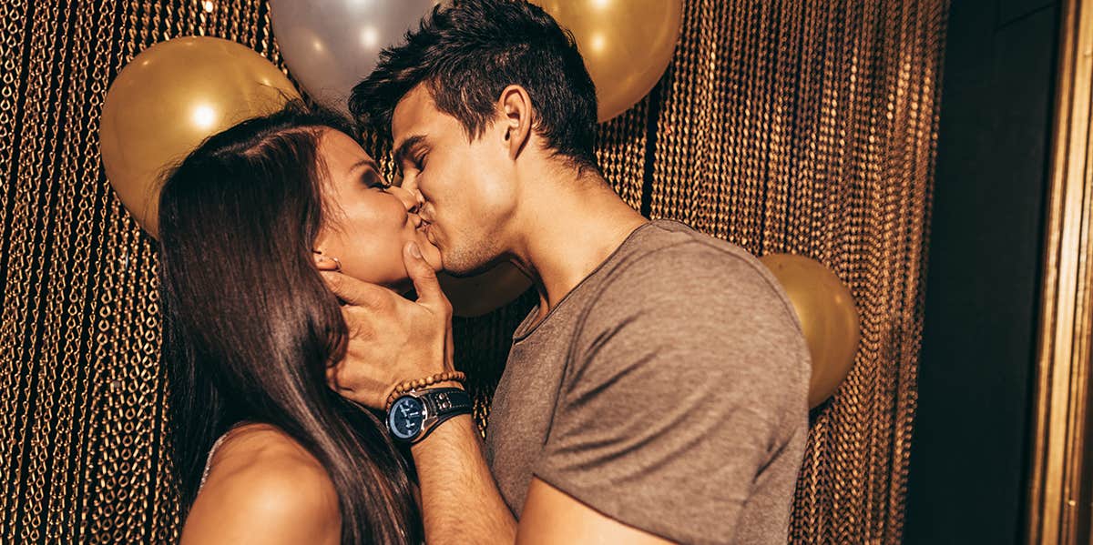 man kissing woman with balloons in background