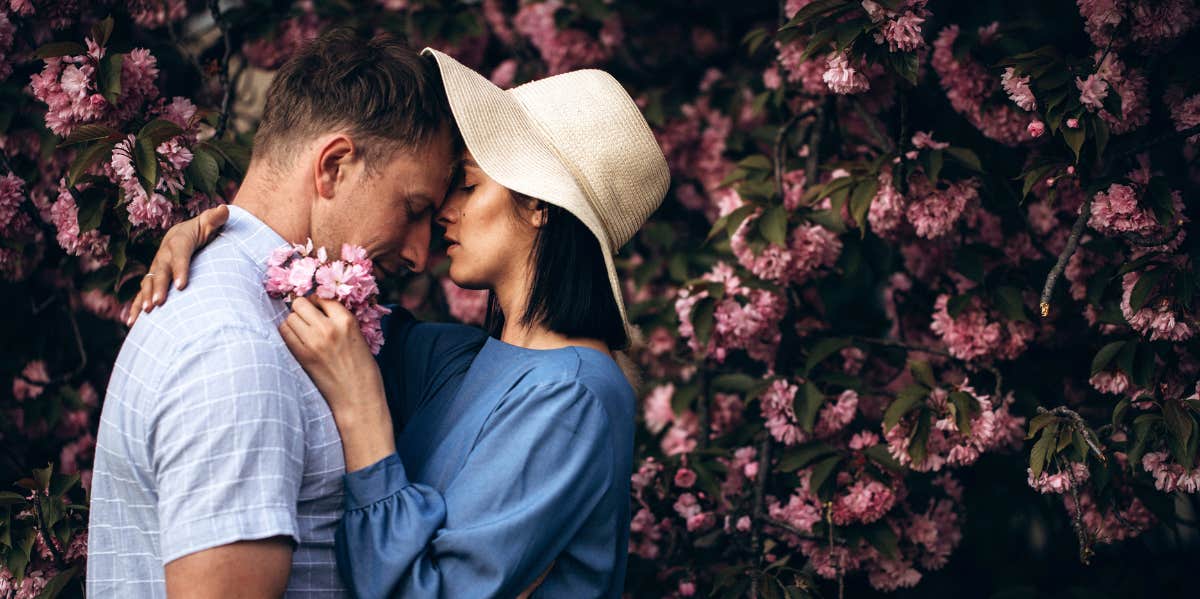 woman and man hugging in front of hedge 