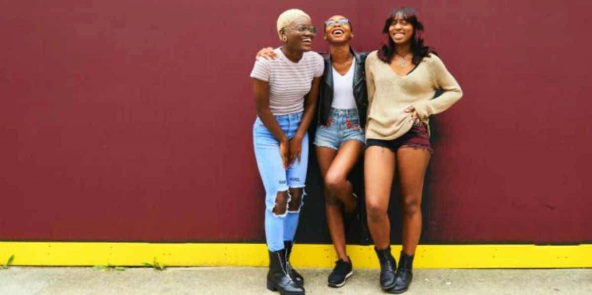 friends laughing together in front of a wall