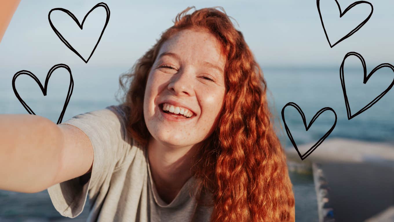 Young woman with long red hair smiling, hearts surrounding her