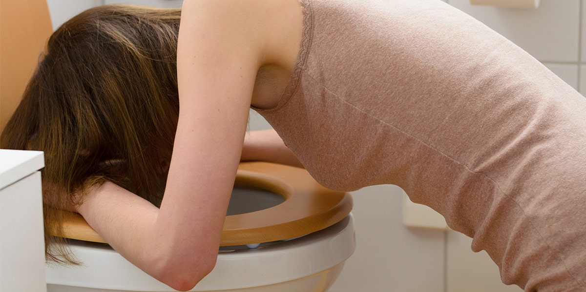 woman vomiting over the toilet