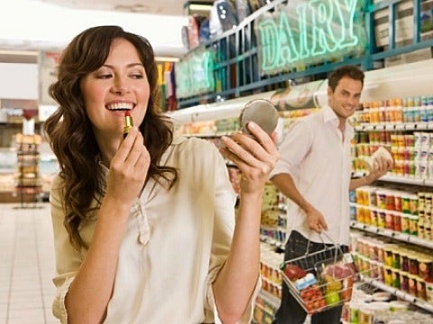 girl putting on makeup at grocery store