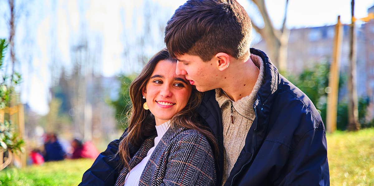 man cuddling smiling woman