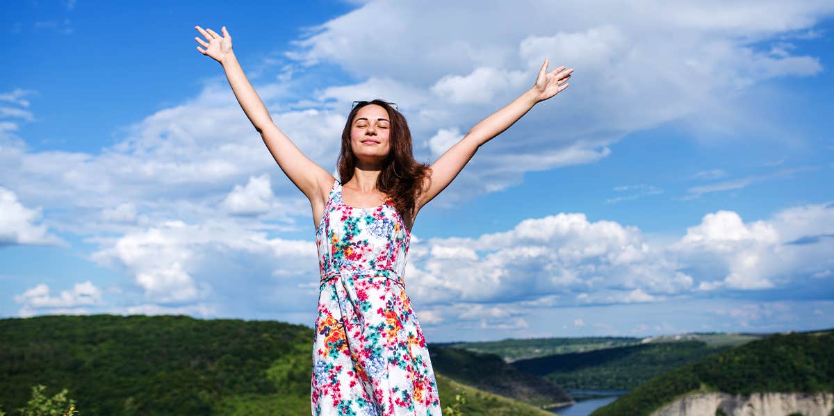 woman holding her arms up to the sky