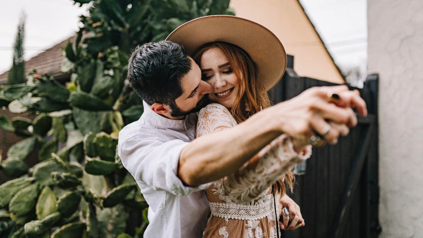 man standing behind woman holding her arm