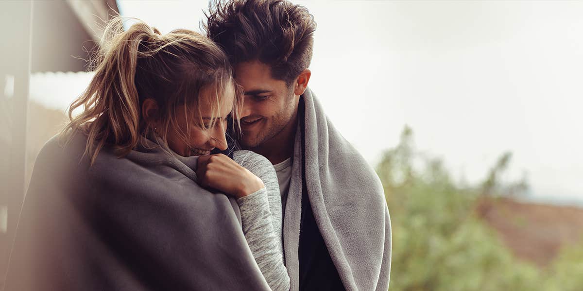 man and woman cuddling in blankets