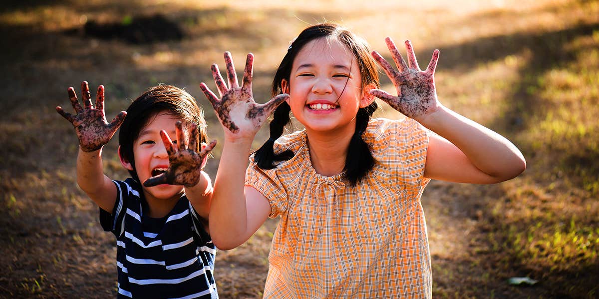 brother and sister with messy hands after playing outside