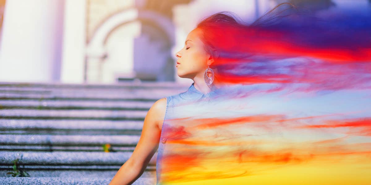 a woman who is calm has a double exposure abstract colorful smear of light trailing behind her