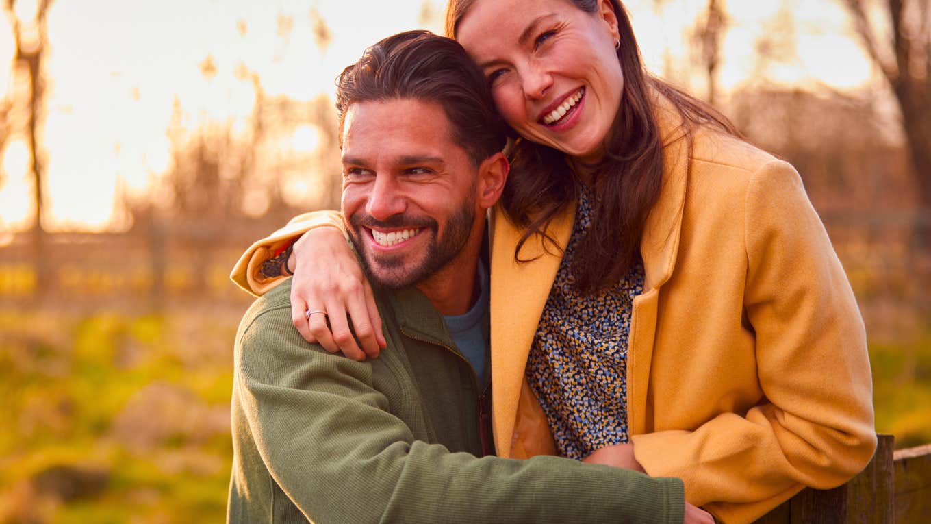 loving couple on walk through autumn countryside resting on fence together