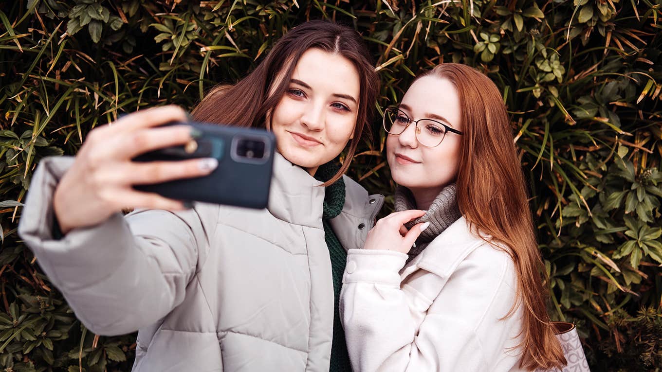 two young girls taking selfie with phone