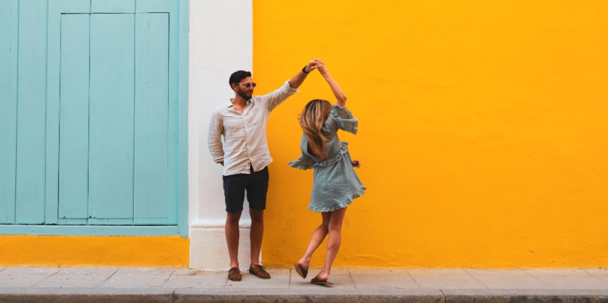 a couple dancing on the street yellow wall background