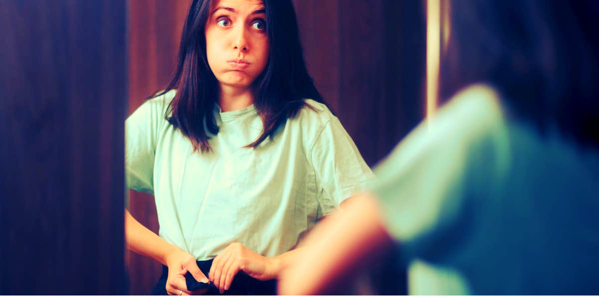 The Big Mistake That Makes You Look Fat & Keeps You Unhappy woman trying on clothes in her old size