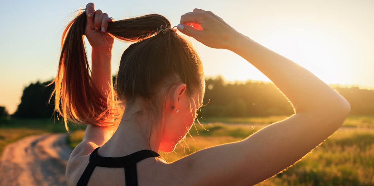 woman putting hair in ponytail