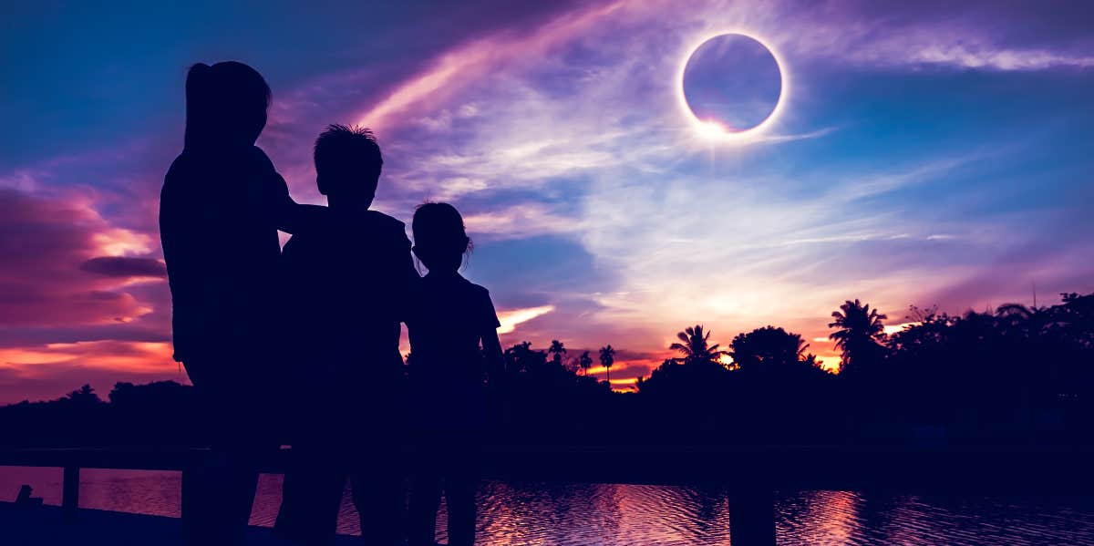 three persons looking at solar eclipse