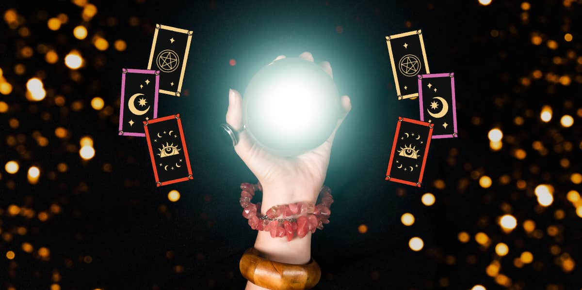 hand holding up a crystal ball with tarot cards 